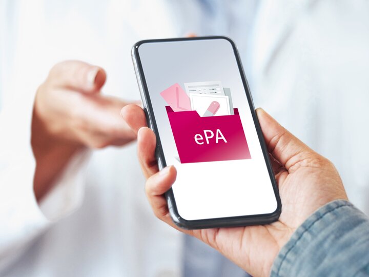 Smartphone mit Bild zur elektronischen Patientenakte wird von einer Hand in eine andere gereicht.